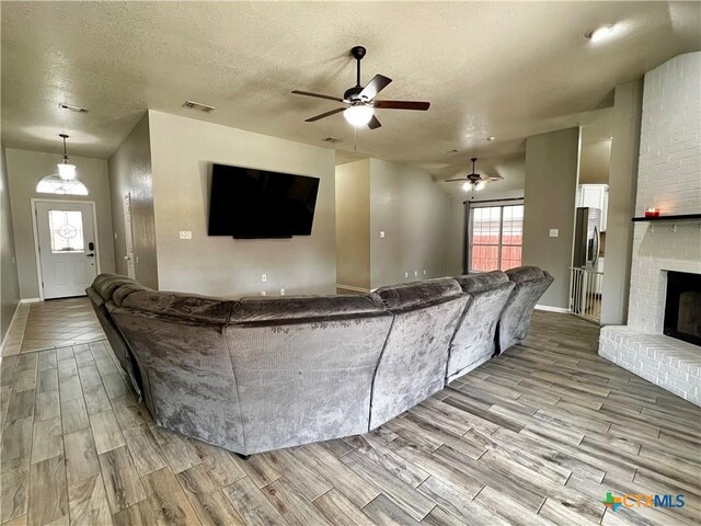 2005 Stonehenge Dr, Harker Heights, TX 76548 - living room with wood finished floors, a ceiling fan, a brick fireplace, and a textured ceiling