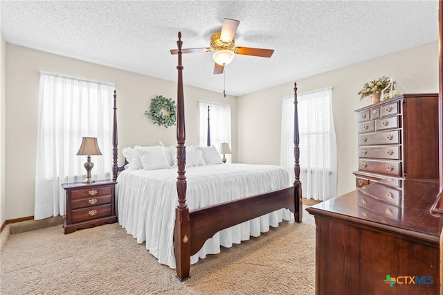 bedroom featuring a textured ceiling, light colored carpet, and ceiling fan