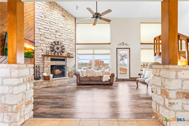 living room featuring a fireplace, a high ceiling, ceiling fan, and wood-type flooring