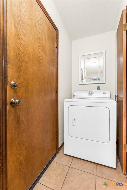 clothes washing area with washer / dryer and light tile patterned floors