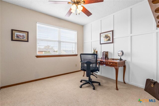 office space featuring a textured ceiling, light colored carpet, and ceiling fan