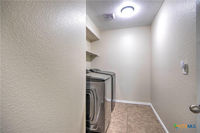 laundry room featuring light tile patterned flooring, washer and dryer, and a textured ceiling