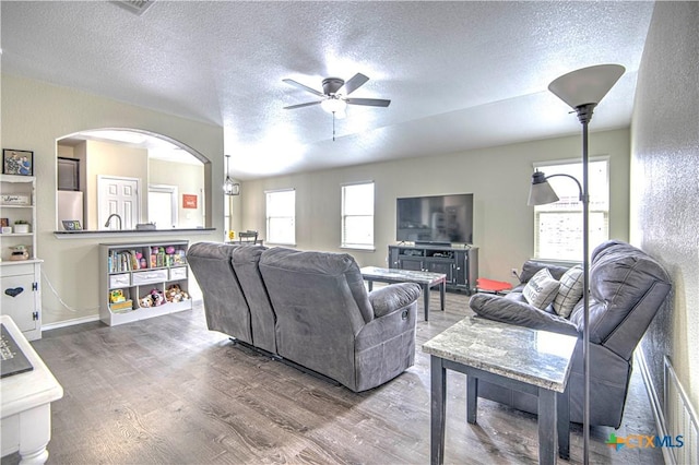 living room featuring ceiling fan, wood-type flooring, and a textured ceiling