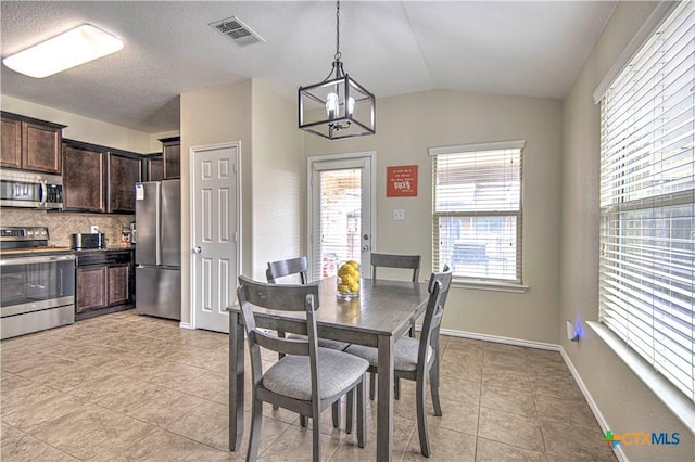 dining room featuring light tile patterned floors, a notable chandelier, vaulted ceiling, and a textured ceiling