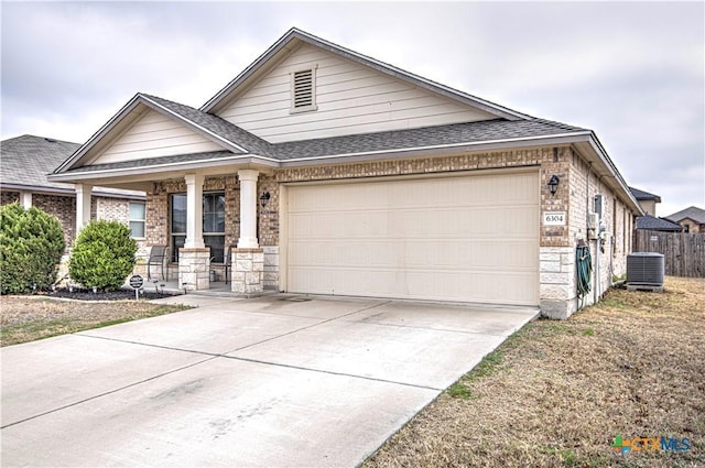 view of front of home featuring a garage, central AC unit, and covered porch