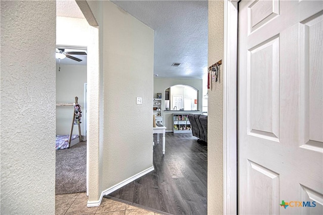 corridor with light tile patterned floors and a textured ceiling