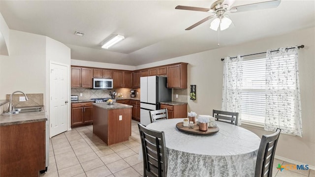 234 Wild Plum, San Marcos, TX 78666 - kitchen featuring a sink, freestanding refrigerator, a center island, light tile patterned floors, and backsplash