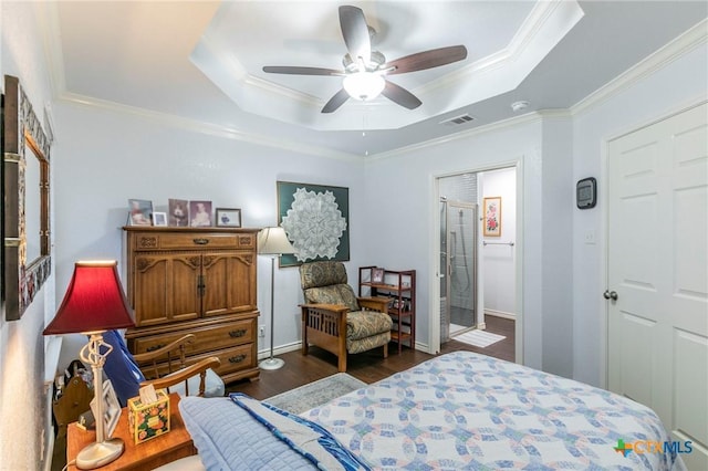 bedroom featuring a tray ceiling, ensuite bath, dark hardwood / wood-style flooring, and crown molding