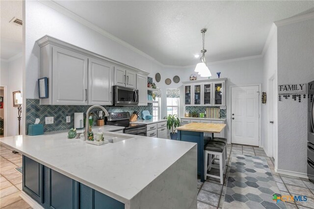 kitchen featuring a kitchen bar, sink, wooden counters, stainless steel appliances, and kitchen peninsula