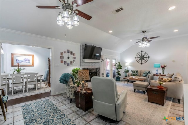 living room with a fireplace, lofted ceiling, ceiling fan, crown molding, and light tile patterned flooring