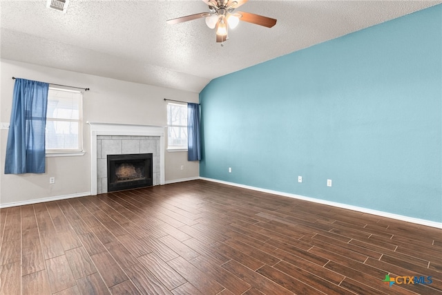 unfurnished living room with ceiling fan, lofted ceiling, a textured ceiling, and a tile fireplace