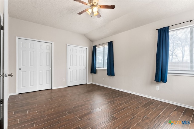 unfurnished bedroom featuring a textured ceiling, two closets, ceiling fan, and lofted ceiling