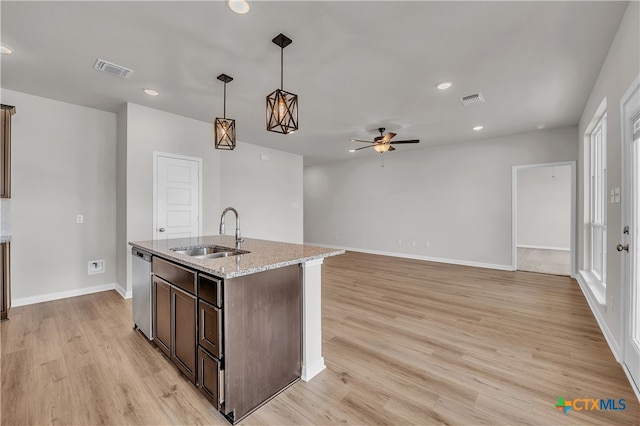 kitchen with light wood-type flooring, light stone countertops, pendant lighting, sink, and stainless steel dishwasher