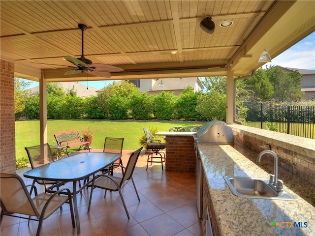 view of patio with area for grilling, a wet bar, ceiling fan, and an outdoor kitchen