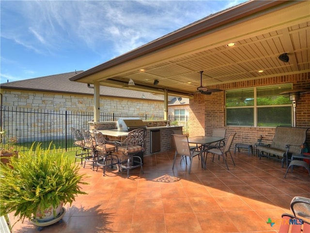 view of patio with ceiling fan, exterior kitchen, an outdoor bar, and area for grilling