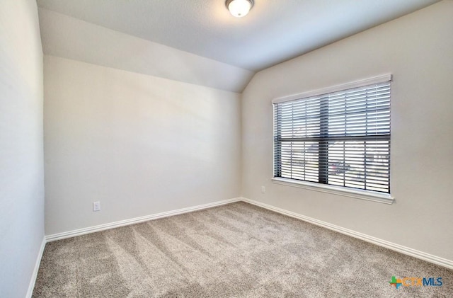 empty room featuring vaulted ceiling and light carpet