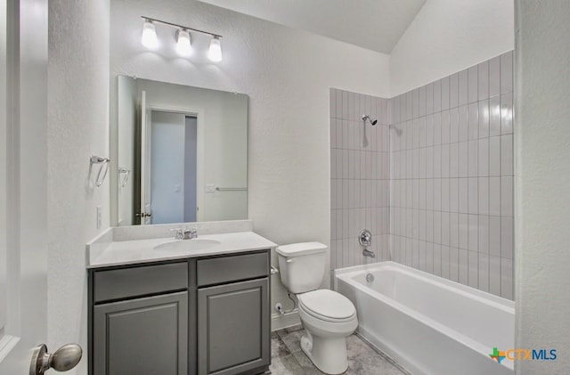 full bathroom featuring toilet, vanity, vaulted ceiling, and tiled shower / bath