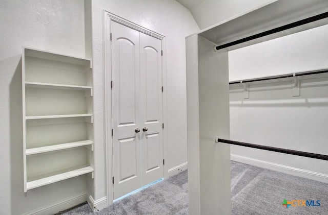 spacious closet with light colored carpet and lofted ceiling