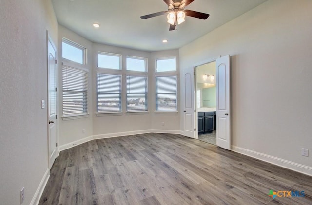 empty room featuring a healthy amount of sunlight, ceiling fan, and wood-type flooring