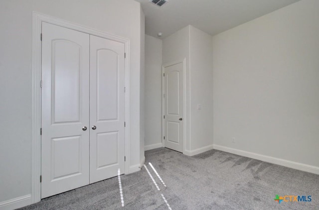 unfurnished bedroom featuring light carpet and a closet