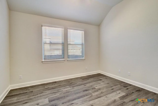 empty room featuring hardwood / wood-style floors and vaulted ceiling