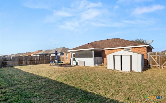 rear view of house with an outbuilding, a fenced backyard, brick siding, a lawn, and a storage unit