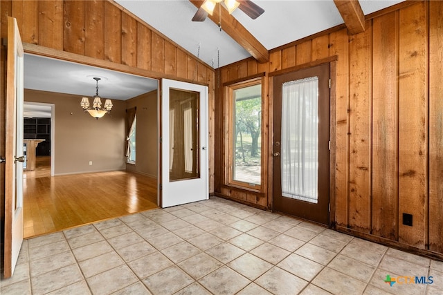 doorway featuring lofted ceiling with beams, wooden walls, ceiling fan with notable chandelier, and light hardwood / wood-style flooring