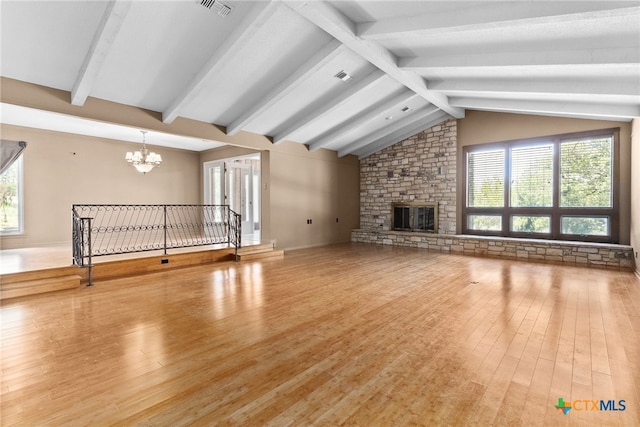 unfurnished living room featuring a stone fireplace, hardwood / wood-style floors, lofted ceiling with beams, and a chandelier