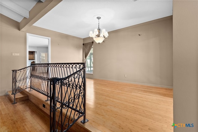 stairs with beamed ceiling, wood-type flooring, a chandelier, and ornamental molding