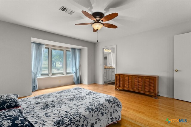 bedroom with light wood-type flooring, ceiling fan, and ensuite bathroom