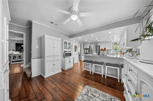 2203 Antelope Trl, Harker Heights, TX 76548 - kitchen featuring stainless steel appliances, white cabinets, a peninsula, dark wood-type flooring, and ornamental molding