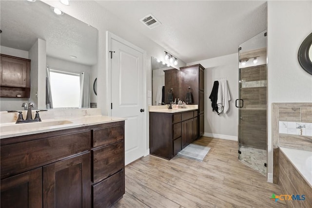 2416 Macdougal St, Nolanville, TX 76559 - full bathroom featuring a stall shower, two vanities, a garden tub, wood finished floors, and baseboards