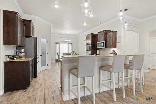 2416 Macdougal St, Nolanville, TX 76559 - kitchen featuring appliances with stainless steel finishes, dark brown cabinetry, tasteful backsplash, a breakfast bar area, and crown molding