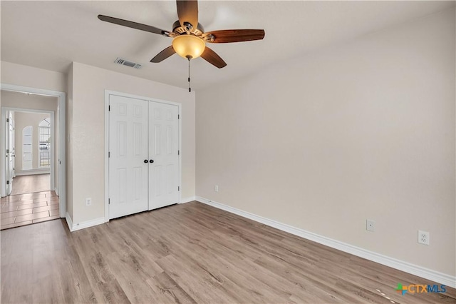 unfurnished bedroom with visible vents, a closet, light wood-style floors, baseboards, and ceiling fan