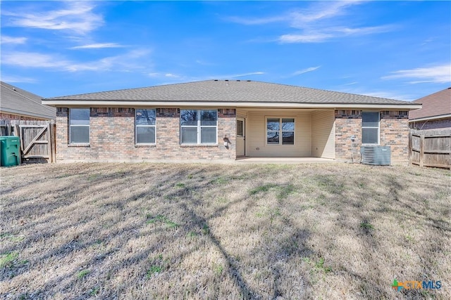 rear view of house featuring a patio, fence, cooling unit, a yard, and brick siding