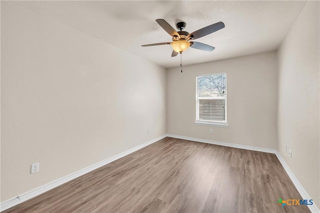 unfurnished room with a ceiling fan, wood finished floors, and baseboards