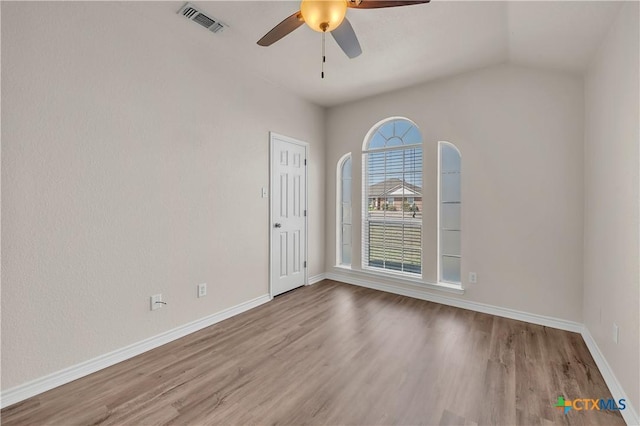 unfurnished room featuring visible vents, wood finished floors, baseboards, ceiling fan, and vaulted ceiling