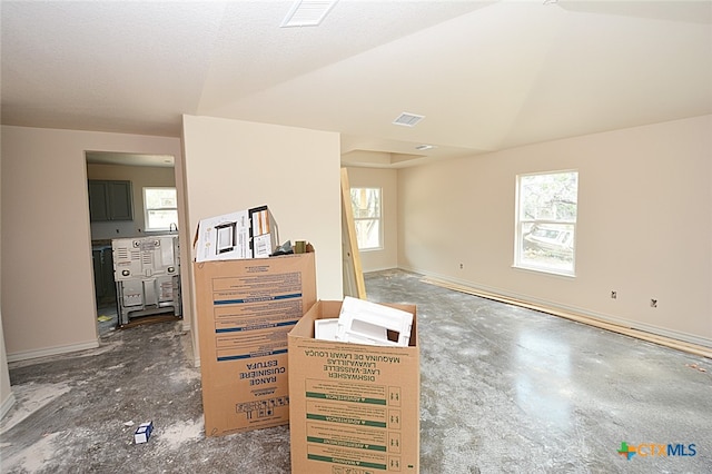 unfurnished room featuring a wealth of natural light, a textured ceiling, and vaulted ceiling