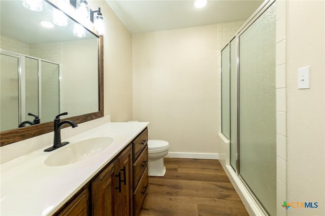 bathroom featuring a shower with shower door, wood-type flooring, toilet, and vanity