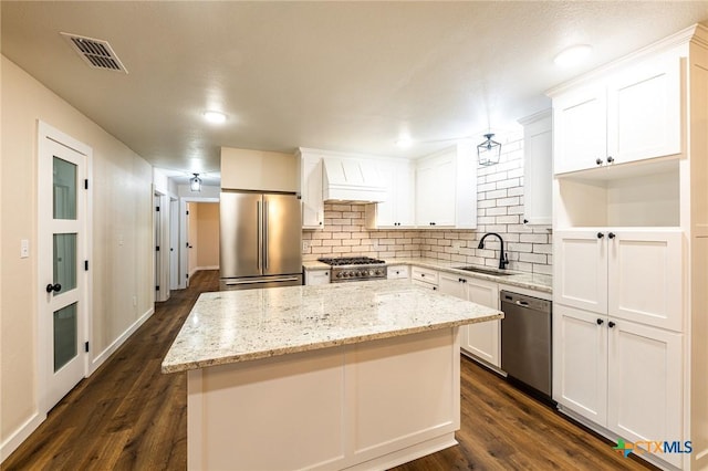 kitchen with appliances with stainless steel finishes, sink, white cabinets, and a center island