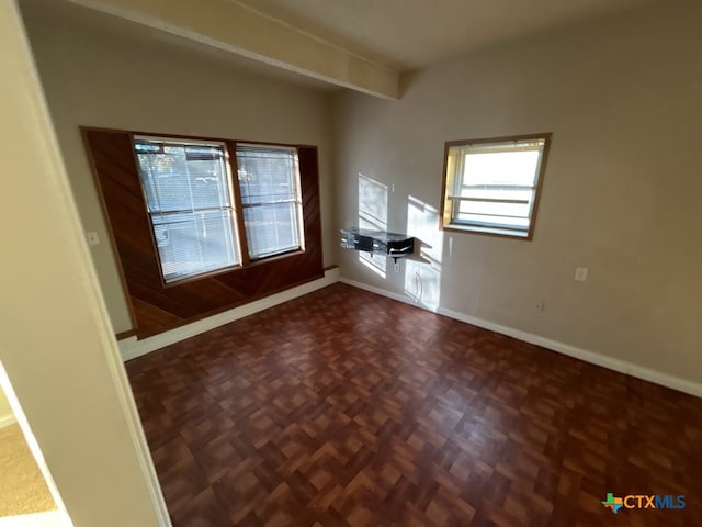 spare room featuring beam ceiling and dark parquet flooring