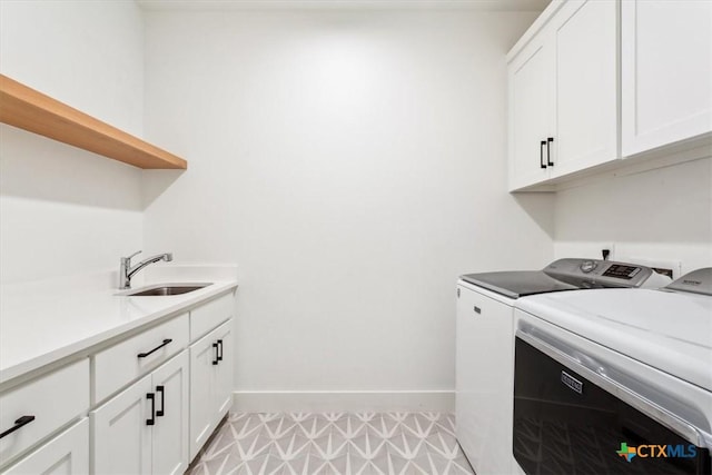 washroom with a sink, baseboards, cabinet space, and washer and dryer