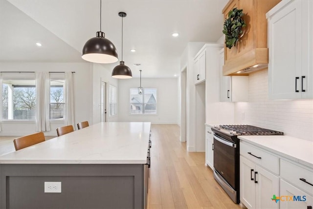 kitchen featuring a kitchen island, range with gas cooktop, white cabinets, light wood finished floors, and decorative backsplash