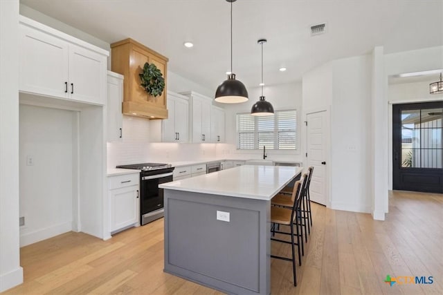 kitchen featuring visible vents, white cabinets, gas stove, and a sink