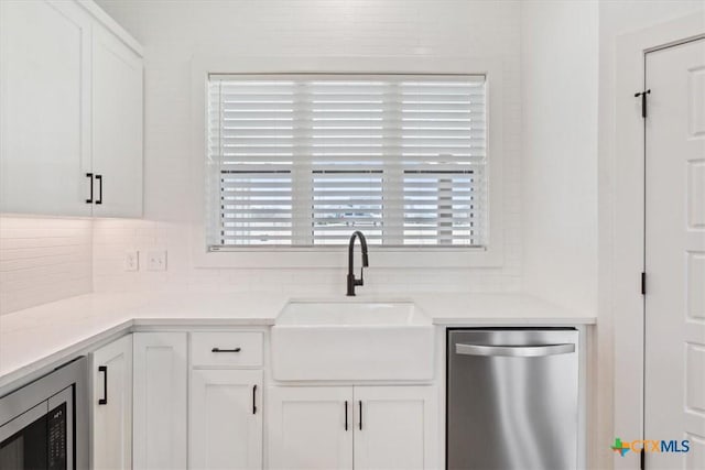 kitchen with white cabinetry, decorative backsplash, appliances with stainless steel finishes, and a sink