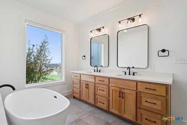 full bath featuring double vanity, a freestanding bath, tile patterned flooring, and a sink