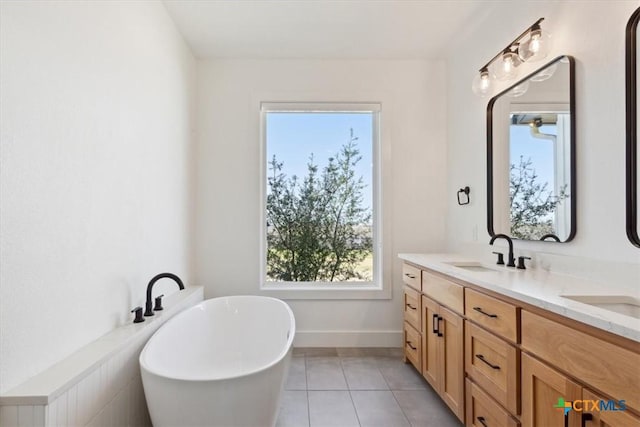 full bath with baseboards, double vanity, a soaking tub, a sink, and tile patterned flooring