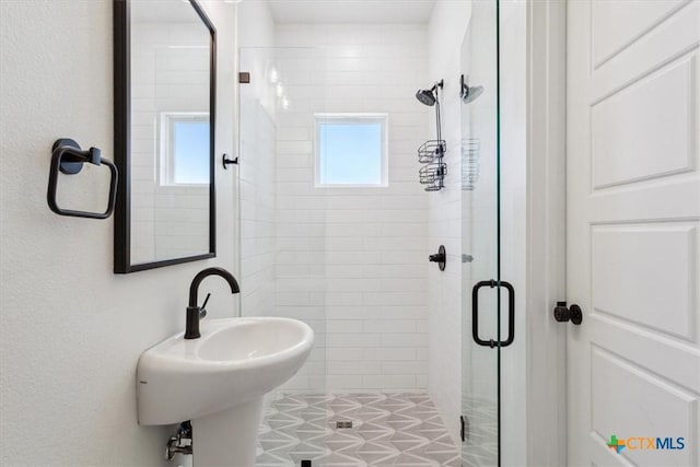 bathroom with a shower stall, a wealth of natural light, and a sink