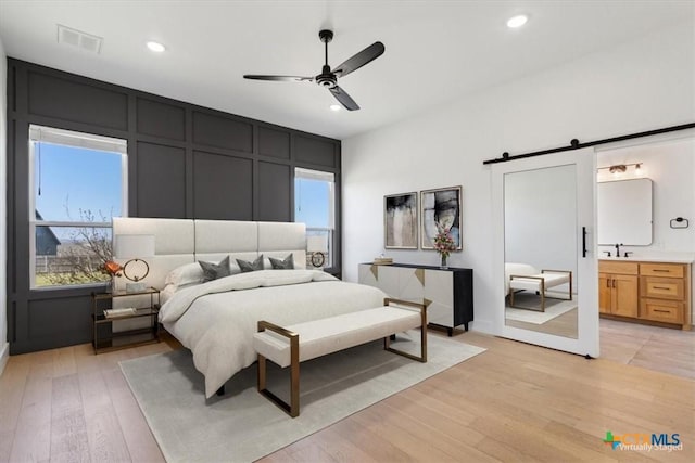 4453 Cedar Creek Rd, Temple, TX 76504 - bedroom with visible vents, multiple windows, a barn door, a decorative wall, and light wood finished floors
