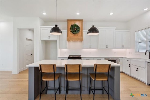 kitchen featuring gas stove, light countertops, white cabinets, light wood-style floors, and a center island